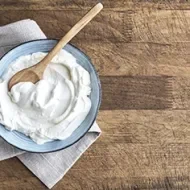 Un plato con yogurt casero recién preparado y una cucharita de madera