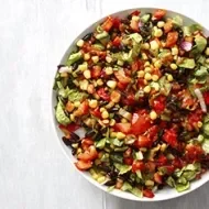 Una ensalada cremosa con maíz, tomate y aguacate en toma cenital