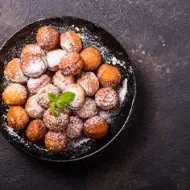 Plato de buñuelos de yuca espolvoreados vistos desde un ángulo cenital.