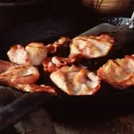 Deliciosa panceta cortada siendo fritada en un sartén