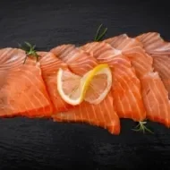 Pequeños trozos de salmón ahumado frío sobre fondo negro.