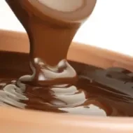 Crema de avellanas, topping habitual en las obleas con fruta. Espesa crema de avellanas vertiéndose en un bowl.