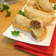 Platillo lleno de empandillas de arroz sobre servilleta roja y junto a un pimiento.