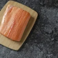 Filete de salmón fresco, uno de los tipos de salmón más usados Filete de salmón fresco sobre tabla de madera