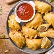Bandeja de empanadas con ají como entrada de comida para fiesta.