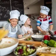 Tres niños preparando recetas alegremente.