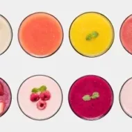 Ocho vasos llenos de smoothies de distintas frutas vistas desde arriba.