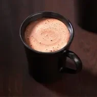 Dos tazas de chocolate caliente con espuma sobre superficie oscura, estilo artesanal.