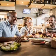 Comensales disfrutando de una comida en restaurante elegante con atención personalizada.