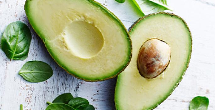 Aguacate partido por la mitad y hojas de espinaca alimentación balanceada Aguacate partido por la mitad y hojas de espinaca alimentación balanceada