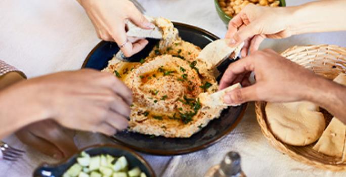 Amigos compartiendo hummus con pan pita, dos comidas mediterráneas. Amigos compartiendo hummus con pan pita, dos comidas mediterráneas.