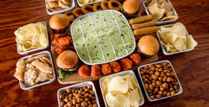 Mesa con botanas fáciles, como frutos secos y papas, para ver deportes. Mesa con botanas fáciles, como frutos secos y papas, para ver deportes.