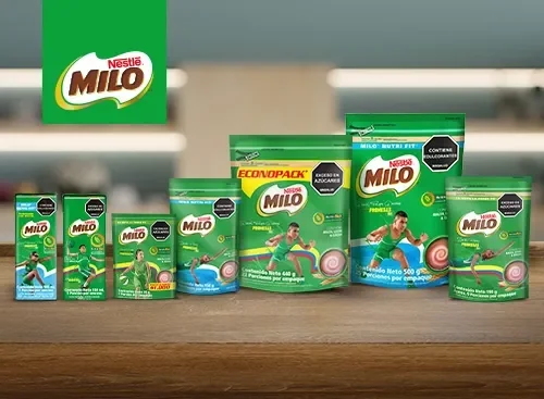 Variedad de productos Nestlé Milo en polvo y líquido exhibidos sobre una mesa, con envases verdes en diferentes tamaños.	